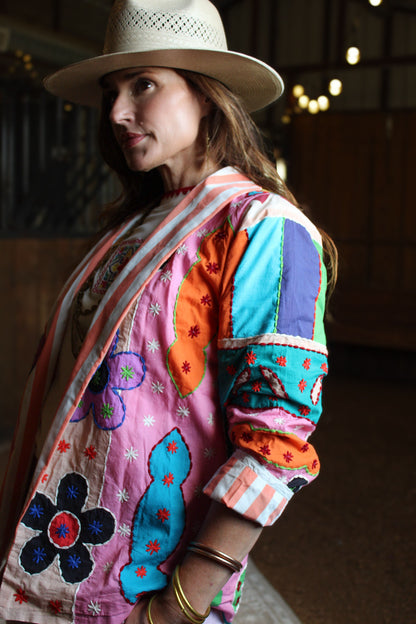 Woman wearing The Tracie Jacket, a pink, orange, and turquoise patchwork statement jacket, styled with a straw western hat for fall